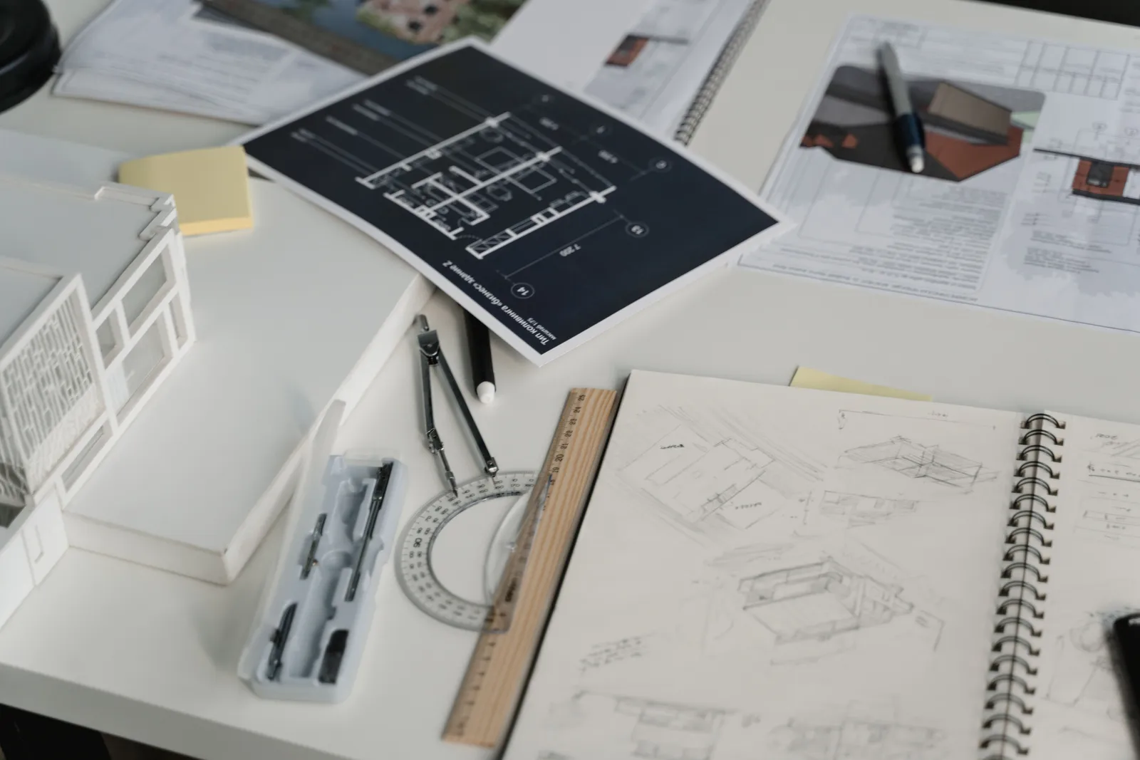 Tavolo di lavoro con disegni tecnici, schizzi di progetto e strumenti da disegno